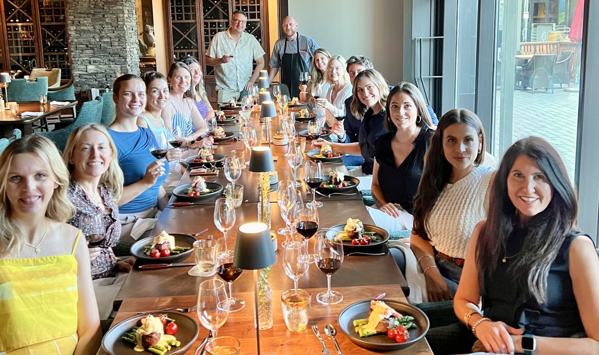 B Line Events team sits at a long dining table smiling at the camera